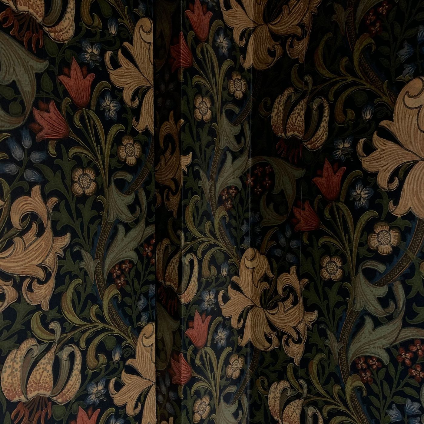 Close-up texture detail of a richly patterned botanical wallpaper in deep green and gold tones, showing crisp panel seams